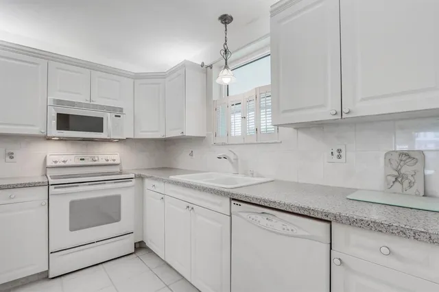 a kitchen with granite countertop white cabinets white stainless steel appliances and a sink