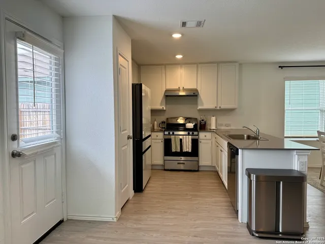 a kitchen with stainless steel appliances a stove top oven a sink and a refrigerator