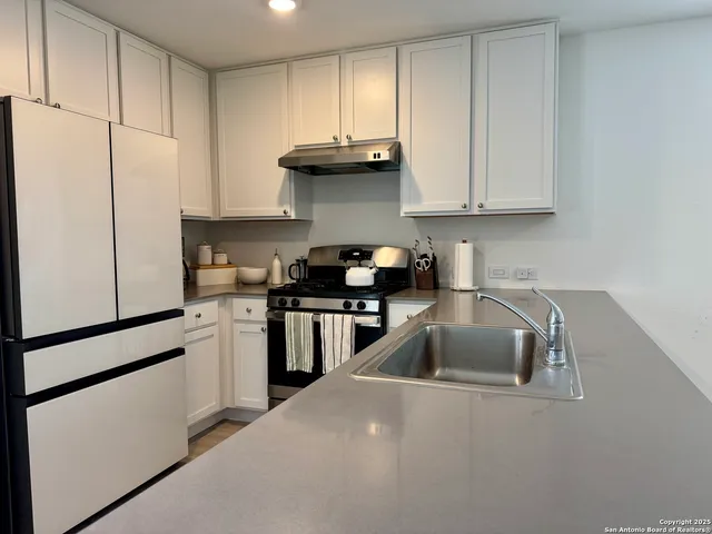 a kitchen with granite countertop white cabinets and stainless steel appliances