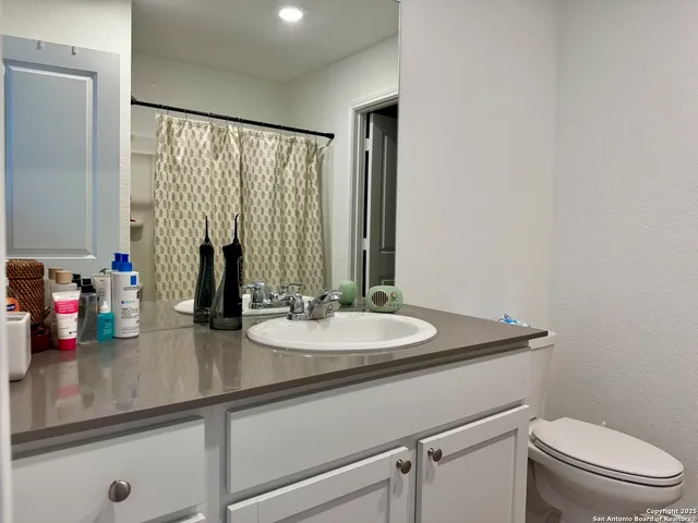 a bathroom with a granite countertop sink a toilet and a mirror