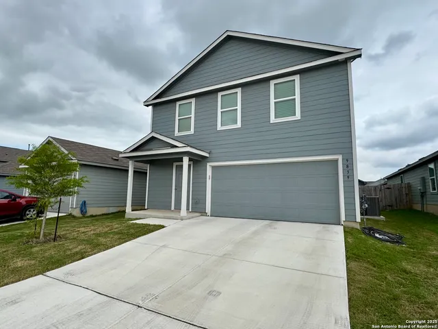 a front view of a house with a yard and potted plants