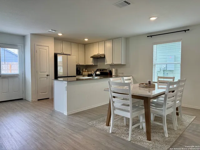 a kitchen with stainless steel appliances a dining table chairs refrigerator and microwave