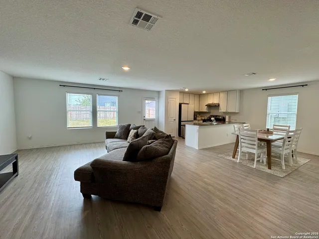 a living room with furniture and a kitchen with wooden floor