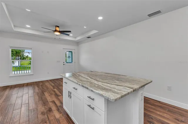 an empty room with wooden floor fan and windows