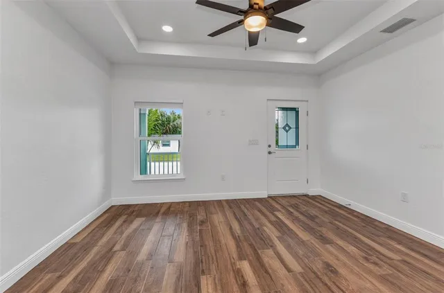 a view of empty room with wooden floor and fan