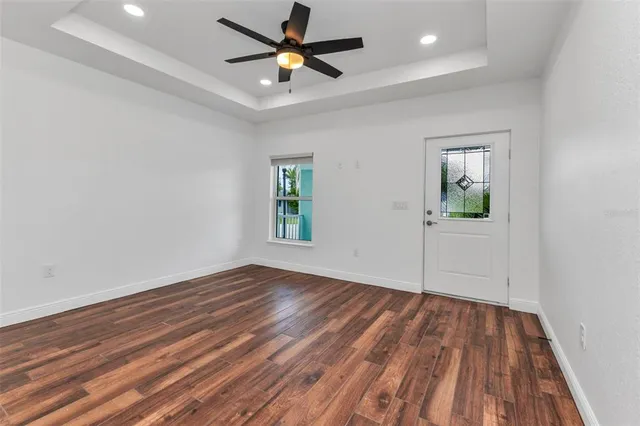 a view of an empty room with a window and wooden floor