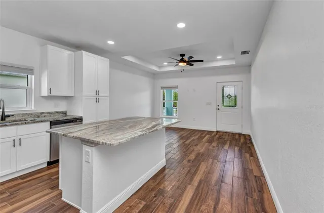 an empty room with wooden floor cabinet and windows