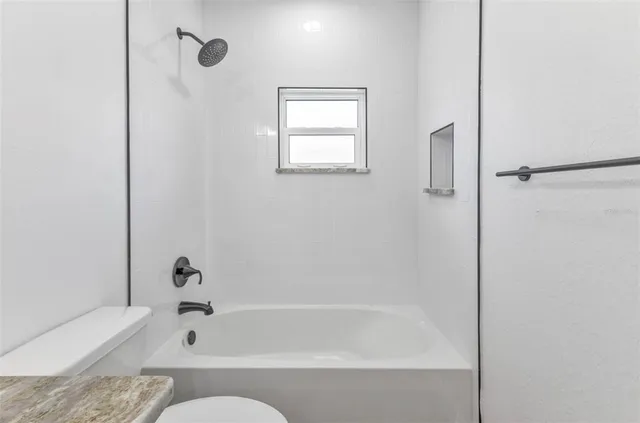 a bathroom with a granite countertop toilet a sink and a bathtub