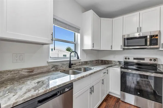 an empty room with wooden floor chandelier fan and windows