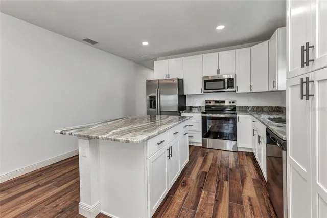 a kitchen with stainless steel appliances granite countertop a sink a stove and cabinets