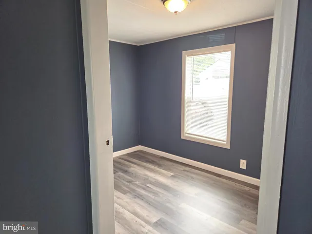 a view of a bedroom with wooden floor and a window