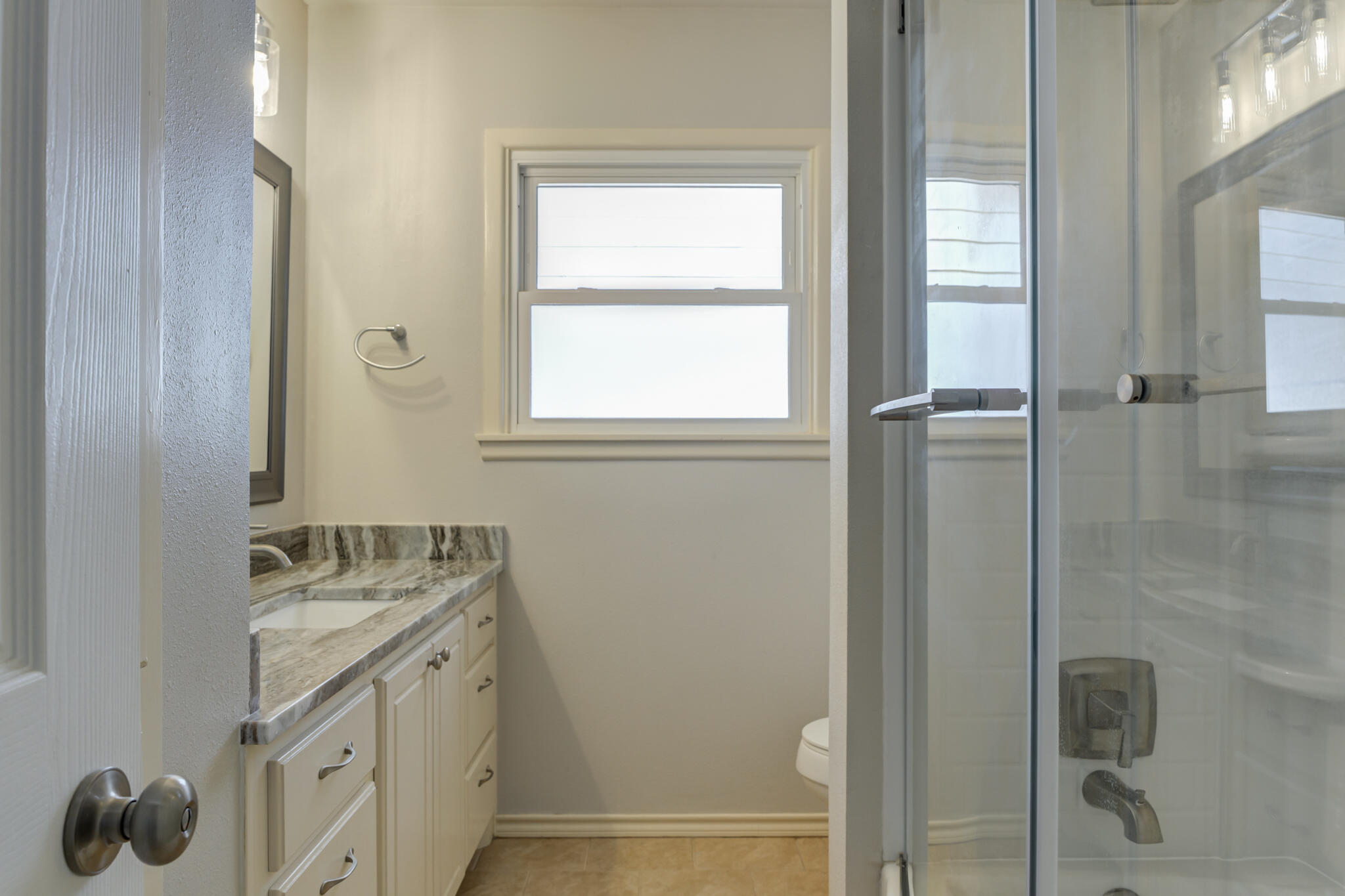 4921 10th Street Lubbock, TX 79416 - Photo 22 of 29 a bathroom with a granite countertop sink a mirror and a shower