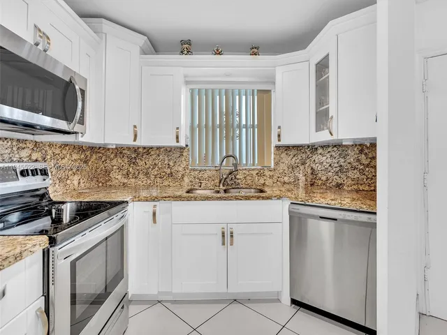 a kitchen with stainless steel appliances granite countertop a refrigerator a stove and a sink