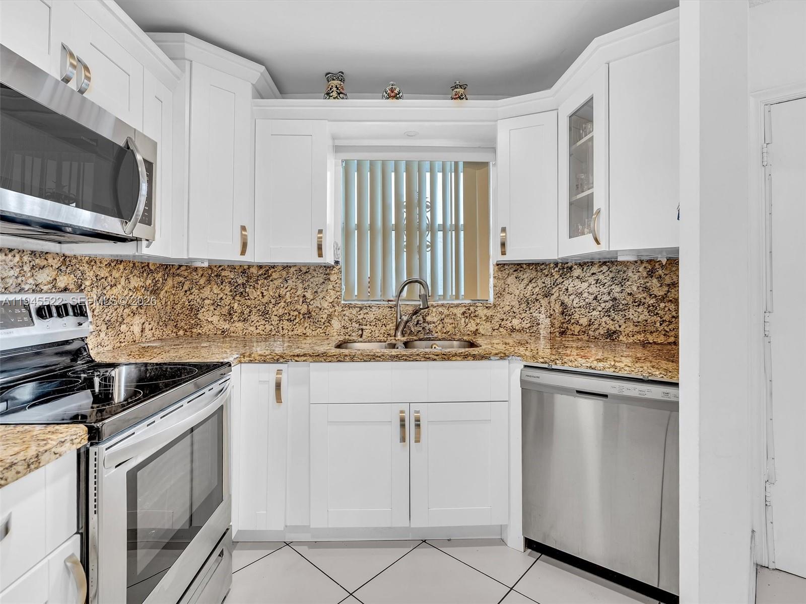 1750 West 46th Street, Unit 404 Hialeah, FL 33012 - Photo 7 of 42 a kitchen with white cabinets sink and appliances