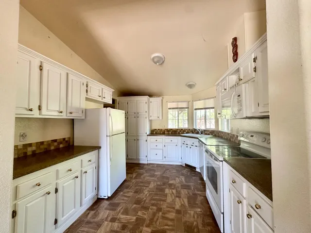 a kitchen with granite countertop a sink stove refrigerator and cabinets