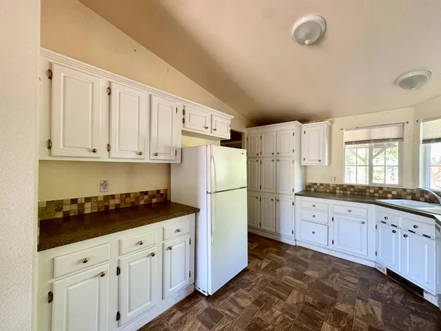 a kitchen with granite countertop white cabinets and refrigerator