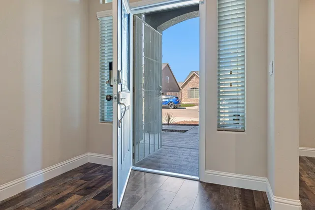 a view of a hallway with wooden floor and a bathroom