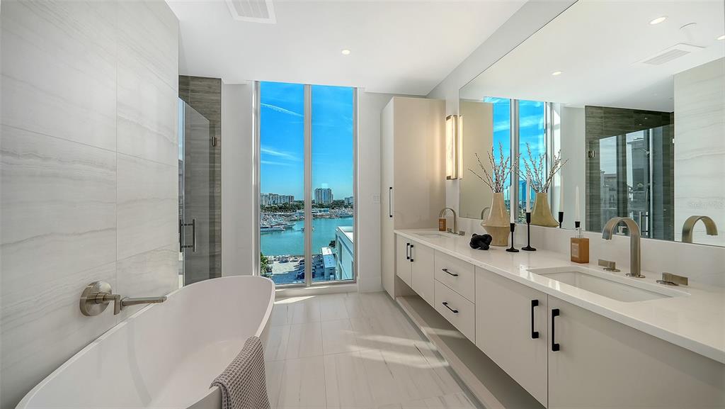 253 Golden Gate Point, Unit 703 Sarasota, FL 34236 - Photo 25 of 51 a bathroom with a double vanity sink a large mirror and a bathtub