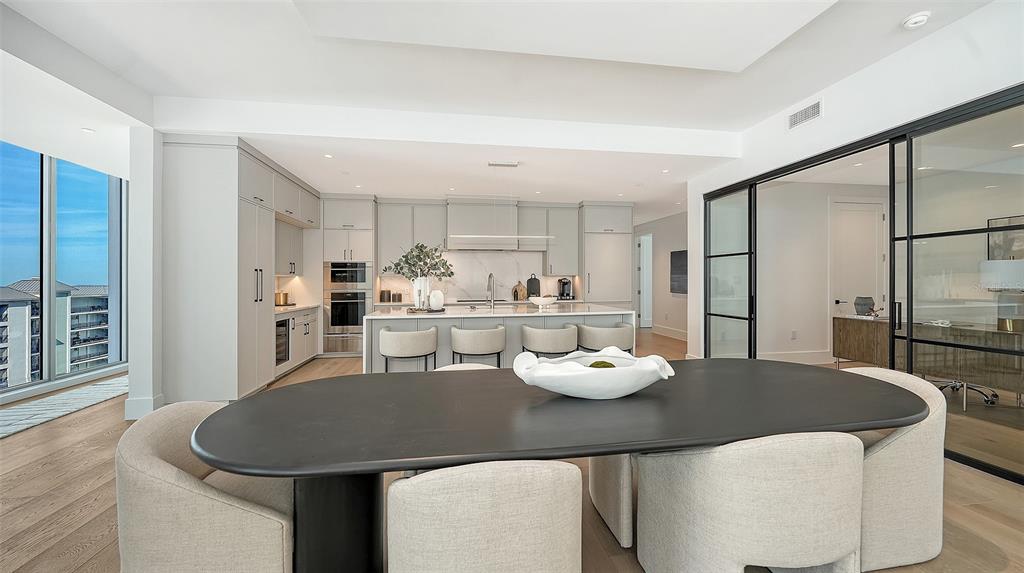 253 Golden Gate Point, Unit 703 Sarasota, FL 34236 - Photo 8 of 51 a kitchen with a table chairs and a refrigerator