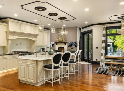 a kitchen with stainless steel appliances granite countertop a stove top oven a sink a dining table and chairs with wooden floor