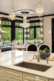 a kitchen with a stove a sink and a dining table with garden view