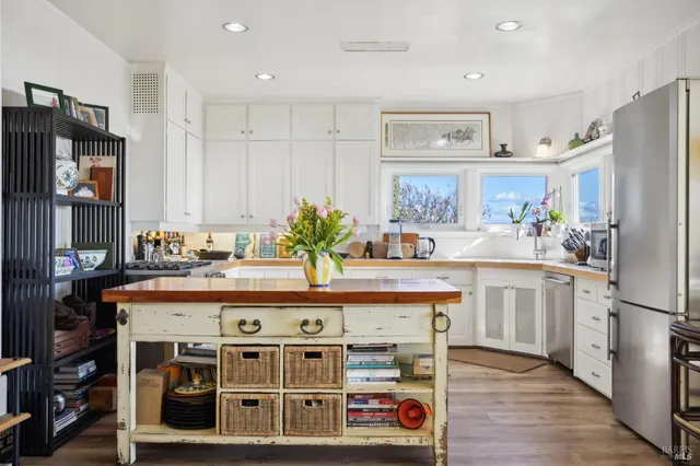 a kitchen with kitchen island a stove a refrigerator and a dining table with wooden floor