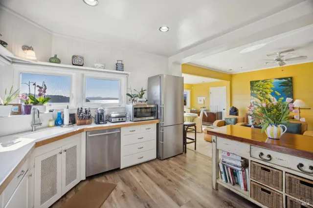 a kitchen with stainless steel appliances a stove a sink and white cabinets with wooden floor