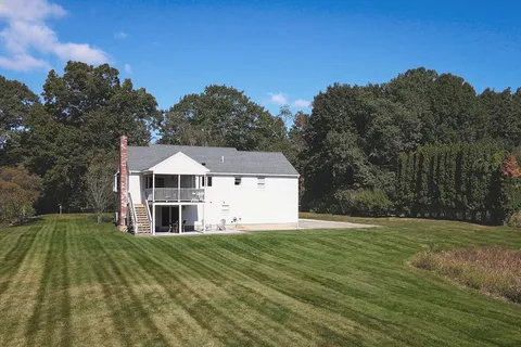 a view of a white house with a big yard and large trees