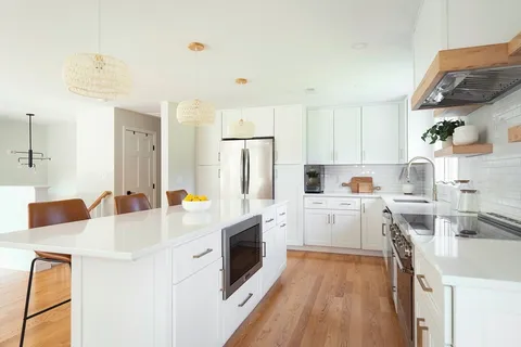a kitchen that has a lot of white cabinets and stainless steel appliances