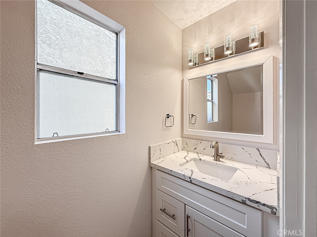 12392 Carl Street Pacoima, CA 91331 - Photo 8 of 55 a bathroom with a granite countertop sink mirror and vanity