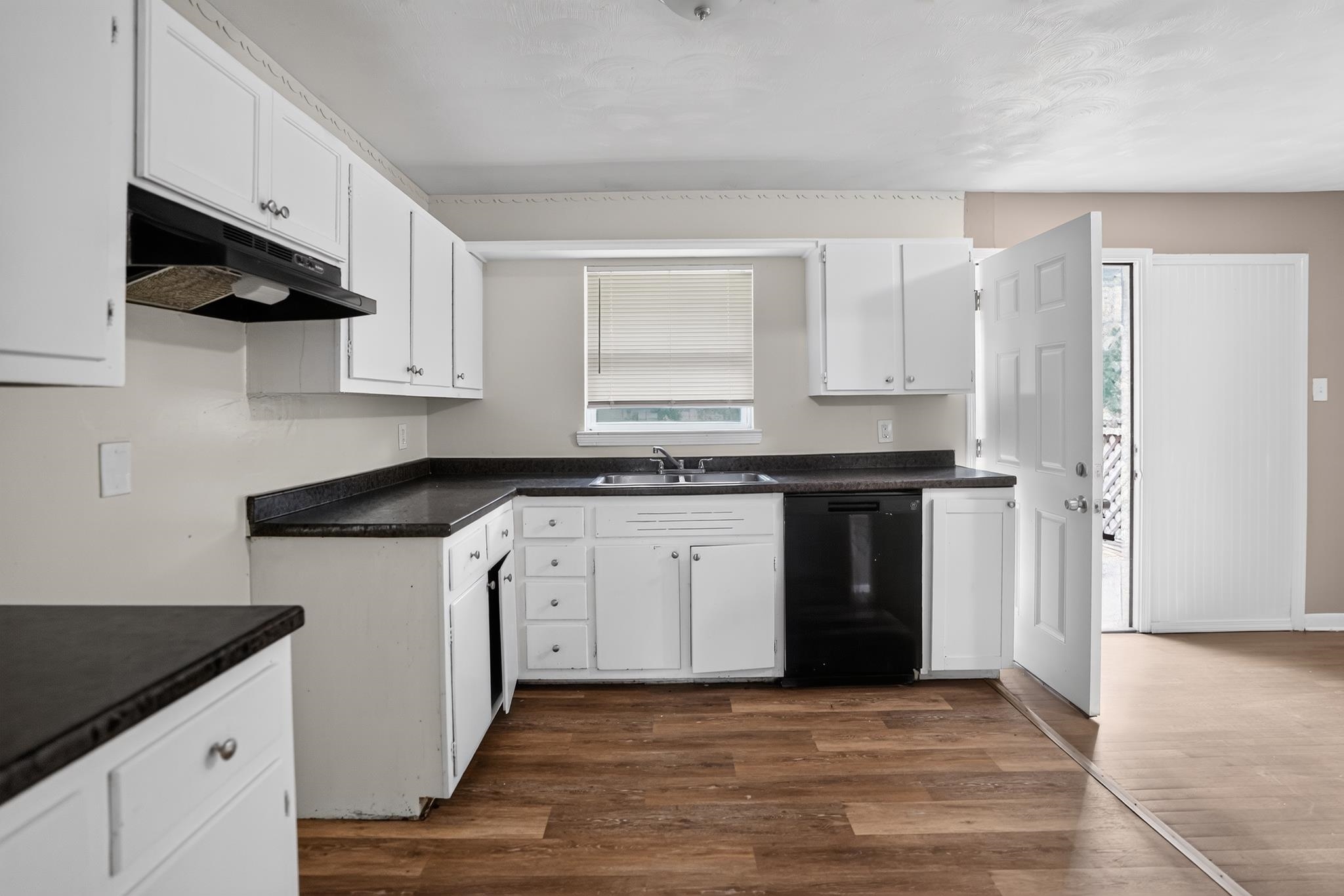 3391 South Perkins Road Memphis, TN 38118 - Photo 7 of 16 Kitchen featuring white cabinetry, dark countertops, a stainless steel sink, a black dishwasher, and wood-finish flooring