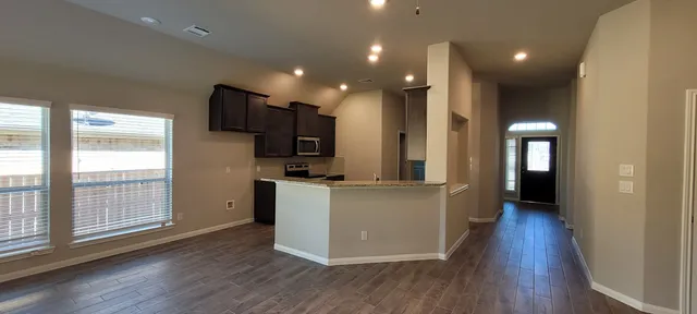 a view of a kitchen with wooden floor and electronic appliances