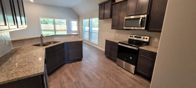 a kitchen with stainless steel appliances granite countertop a stove a sink and a microwave