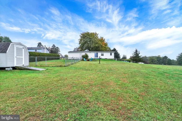 a view of a house with a big yard and large trees