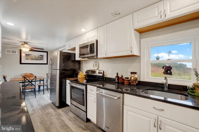 a kitchen with stainless steel appliances granite countertop a sink a stove a microwave a sink a refrigerator and cabinets