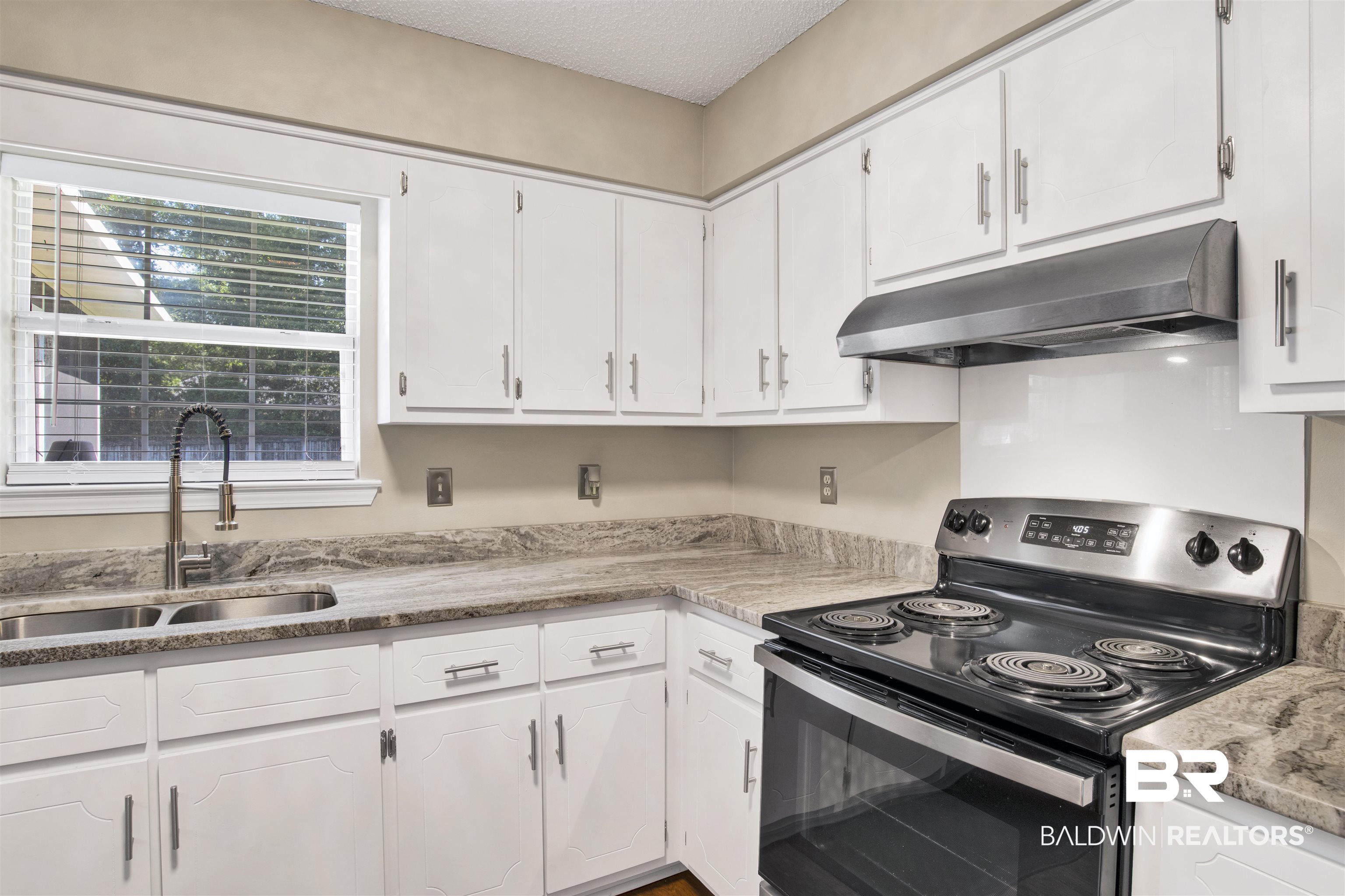 6281 Woodside Drive Theodore, AL 36582 - Photo 8 of 17 Kitchen featuring stainless steel range with electric stovetop, under cabinet range hood, white cabinetry, and a textured ceiling