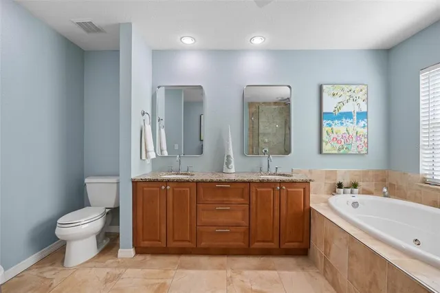 a bathroom with a granite countertop sink mirror bathtub and toilet