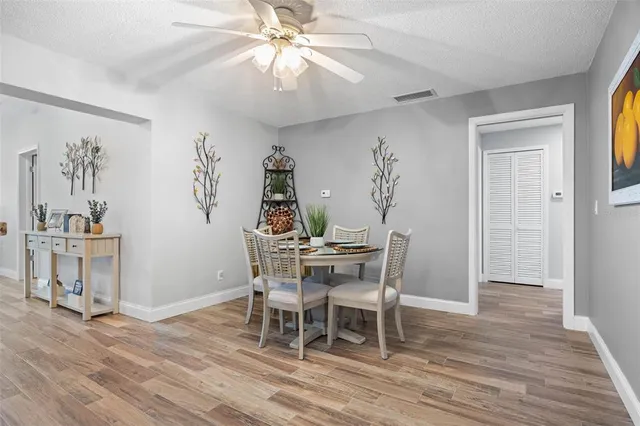 a dining room with wooden floor a chandelier a wooden table and chairs