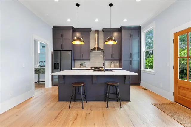 a kitchen with stainless steel appliances granite countertop a sink a stove a refrigerator a dining table and chairs