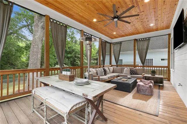 a living room with furniture a flat screen tv and a floor to ceiling window
