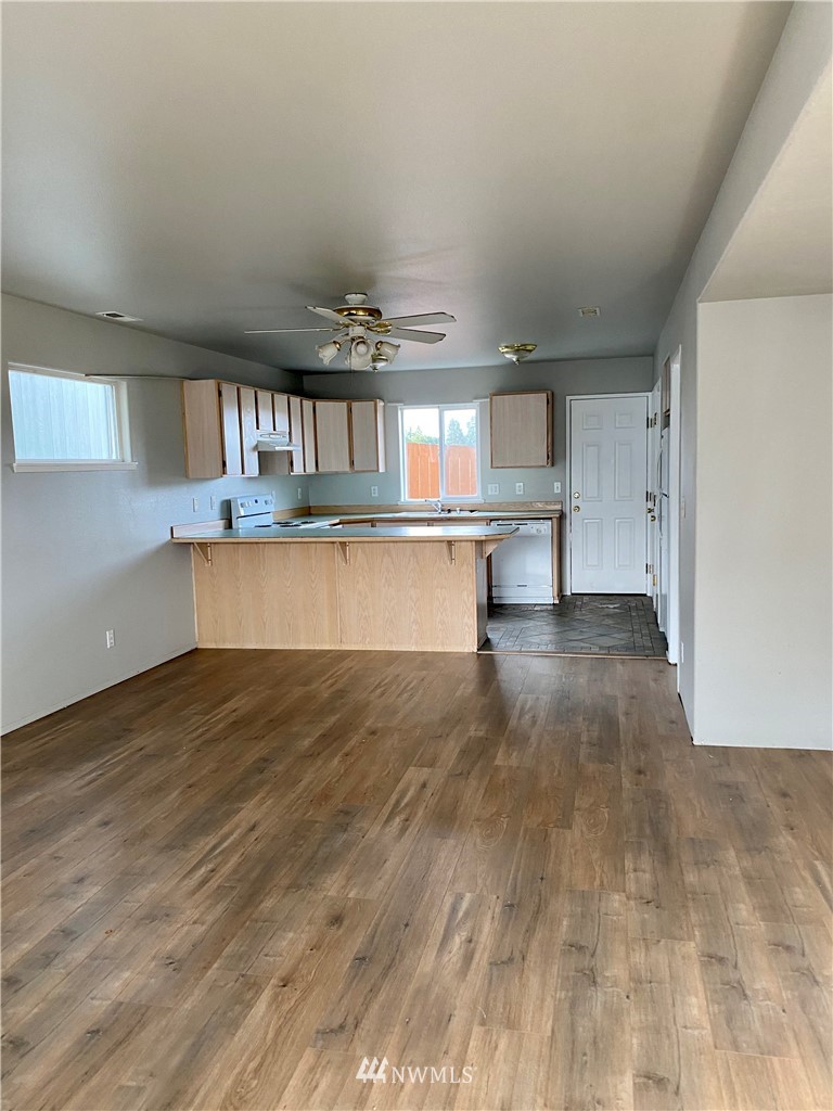 3966 Broadmoor Loop Bremerton, WA 98310 - Photo 14 of 32 a view of a kitchen with kitchen island a sink wooden floor and a counter top space