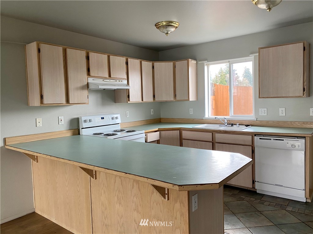 3966 Broadmoor Loop Bremerton, WA 98310 - Photo 8 of 32 a kitchen with stainless steel appliances granite countertop a sink a stove a table and chairs