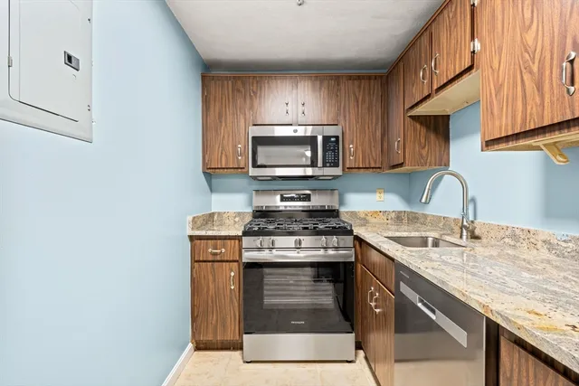 a kitchen with granite countertop wooden cabinets stove top oven and sink