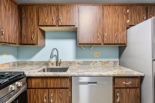 a kitchen with granite countertop wooden cabinets a sink and a stove
