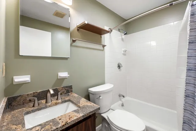 a bathroom with a granite countertop sink toilet and shower