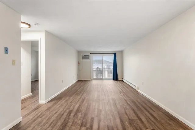 a view of an empty room with wooden floor and window