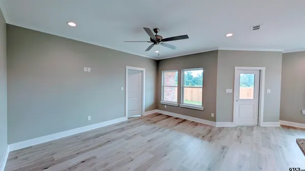 an empty room with wooden floor and windows