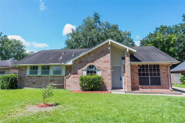a view of a yard in front of a house with plants and large tree