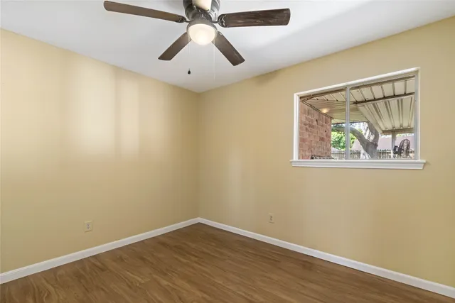 an empty room with wooden floor and ceiling fan