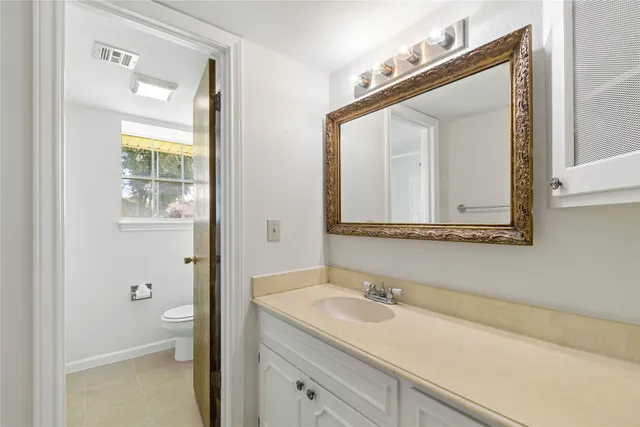 a bathroom with a granite countertop sink a toilet and a mirror